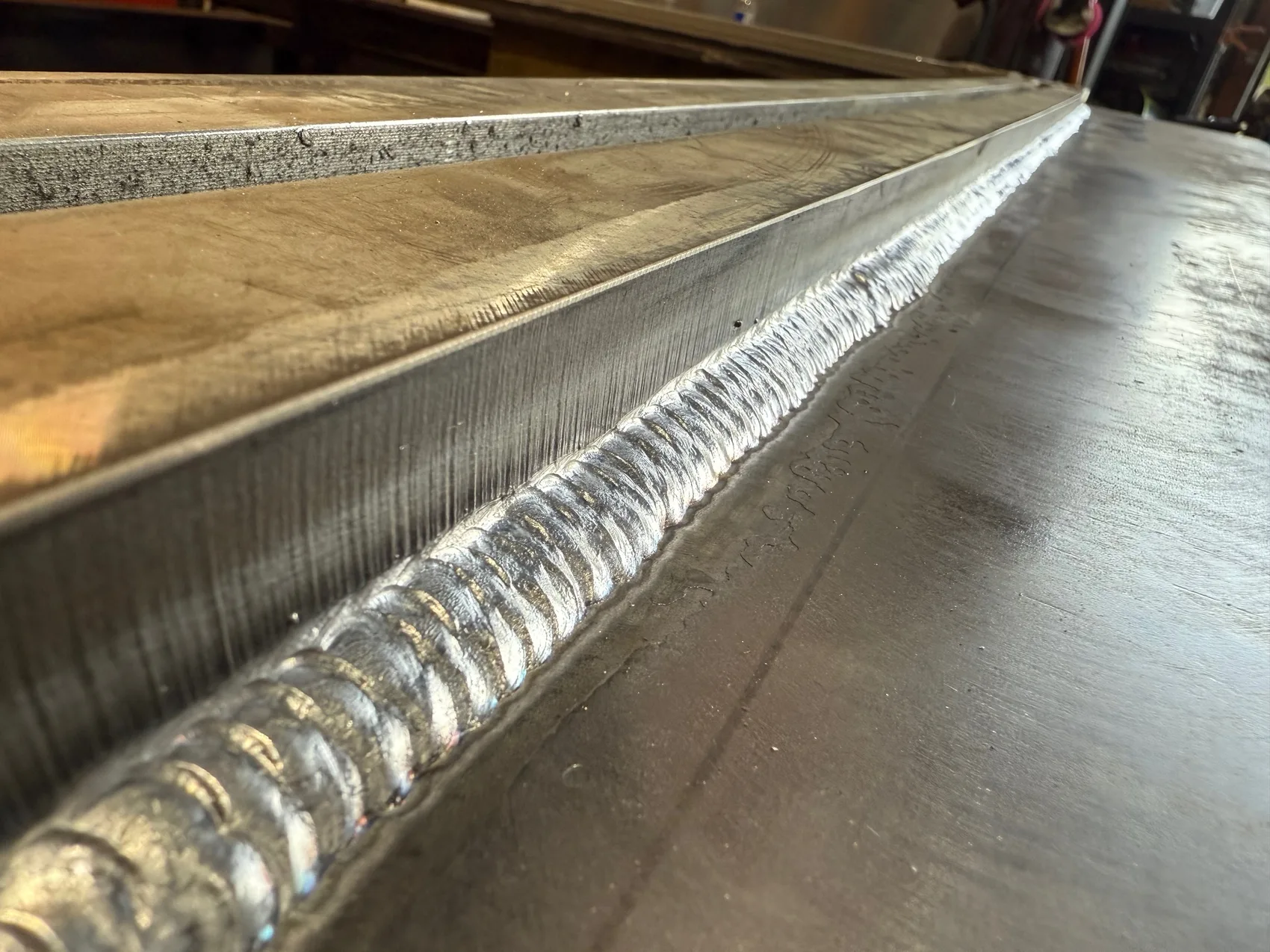 A full-length stacked-dime bead down a door plate seam - continuous and fully fused so the channel holds under pressure.