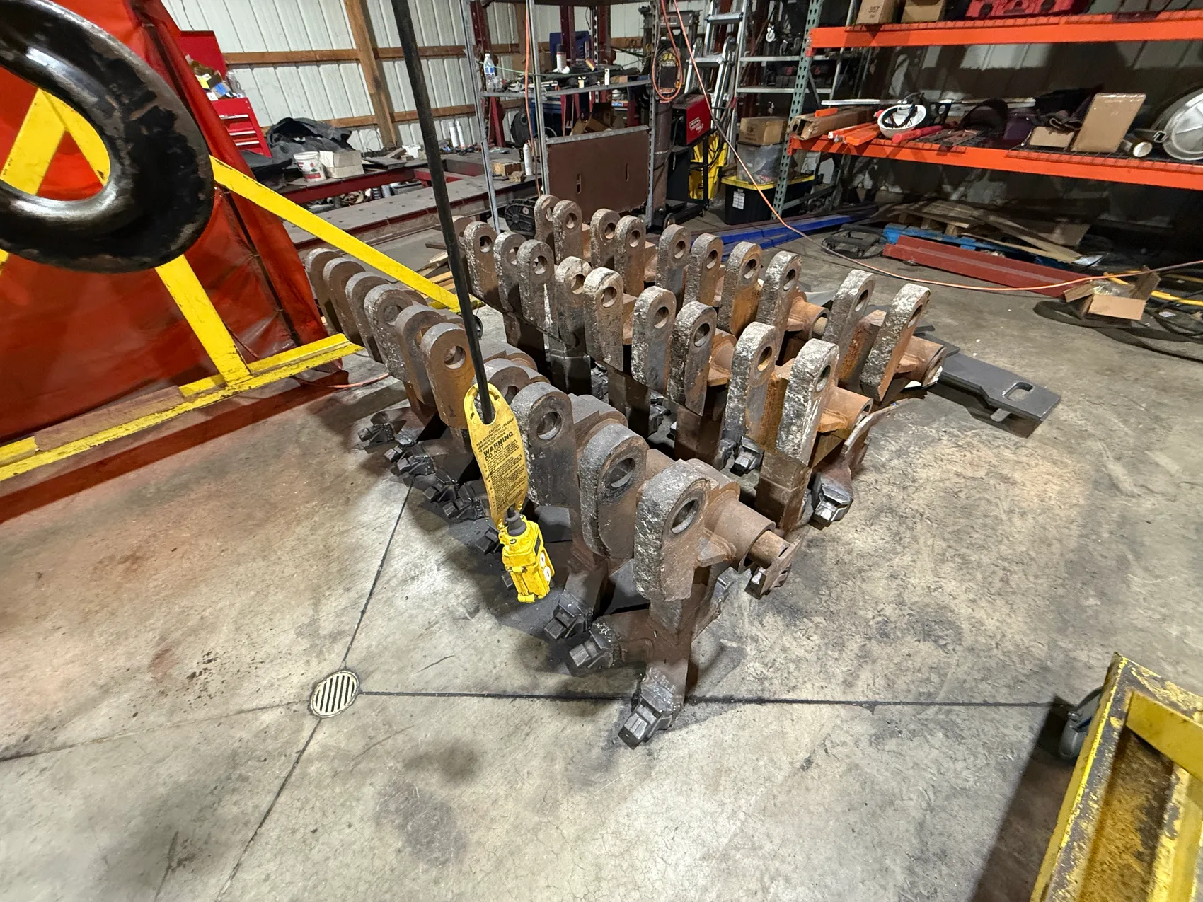 A full production run of forged-link assemblies with welded-on cast teeth, staged on the shop floor at Sons of Thunder Welding