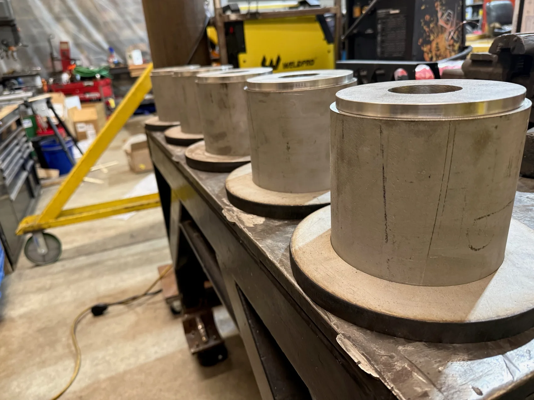 A run of machined stainless steel pulley drums staged in a row on the bench in the Sons of Thunder Welding shop