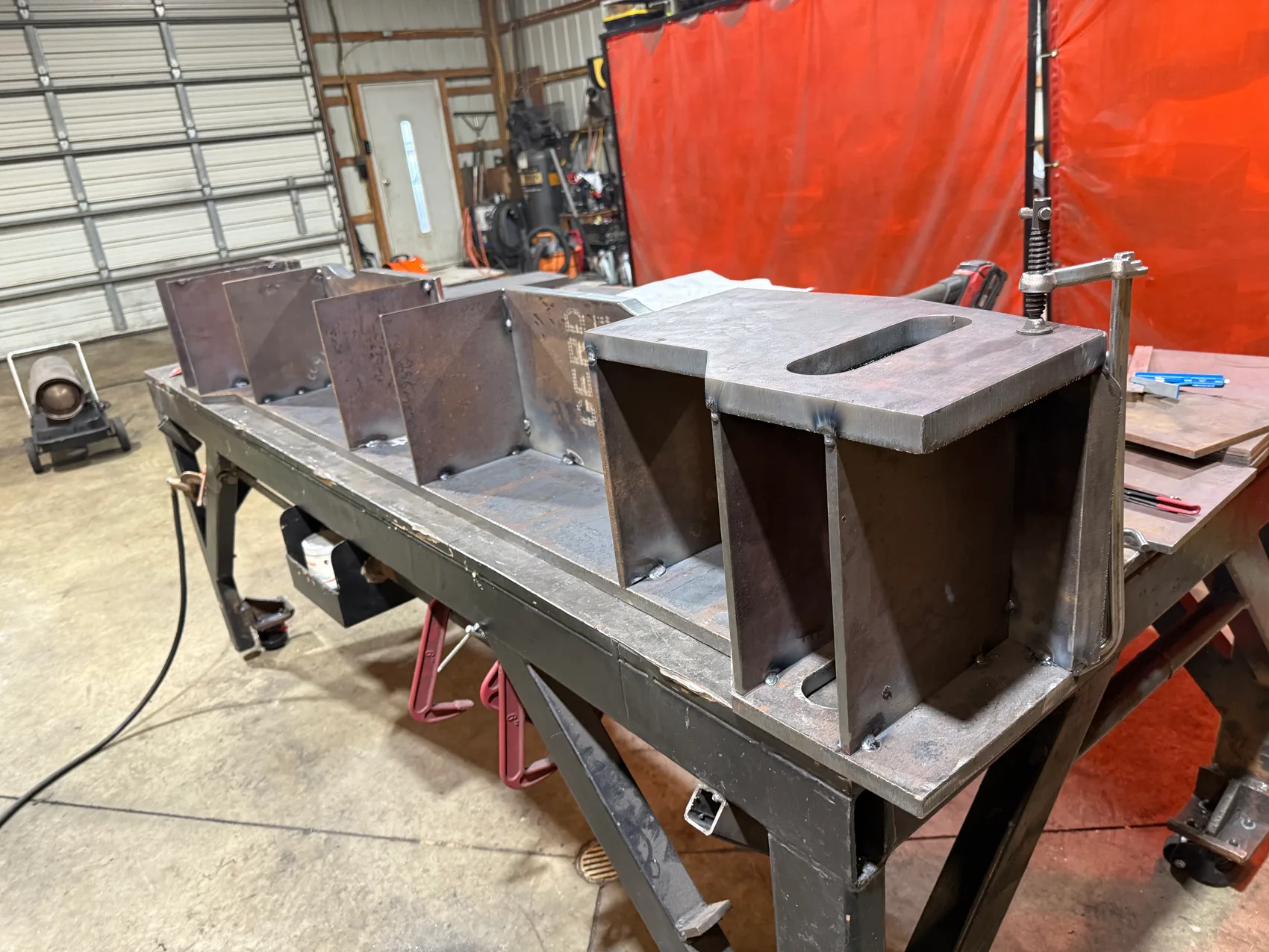 Row of custom steel box housing weldments clamped for fit-up by Sons of Thunder Welding