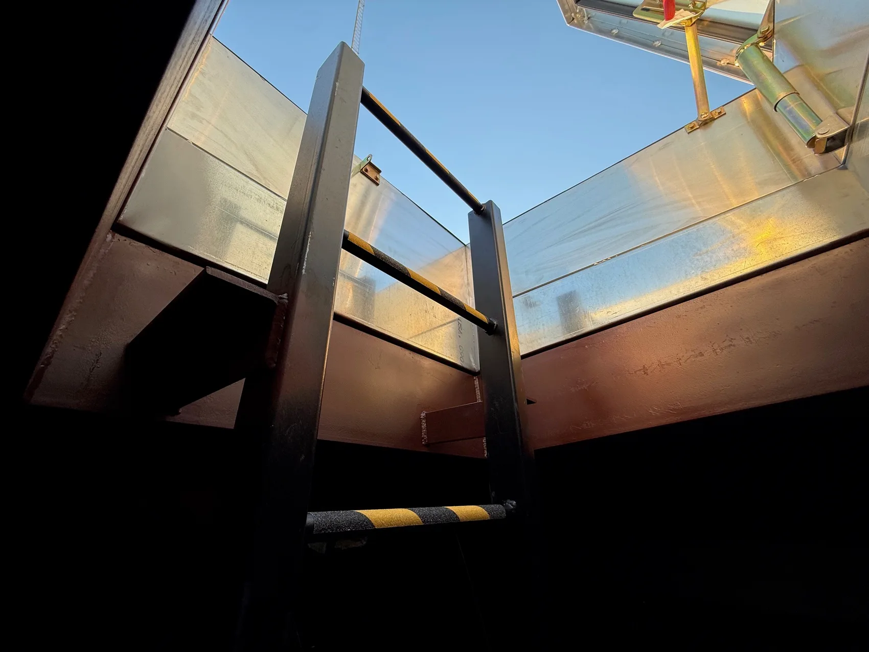 Galvanized caged ladder and structural steel framing leading to a roof hatch by Sons of Thunder Welding